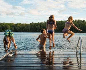 Eine Gruppe Jugendlicher springen in den Badesee